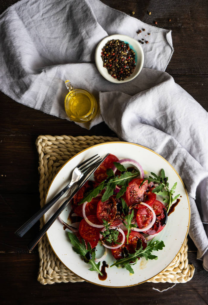 トマト、赤タマネギ、ロケット ハーブとコピー領域と暗い木製のテーブルに亜麻の種子のように有機野菜のサラダの完全セラミック ボウル - 写真・画像