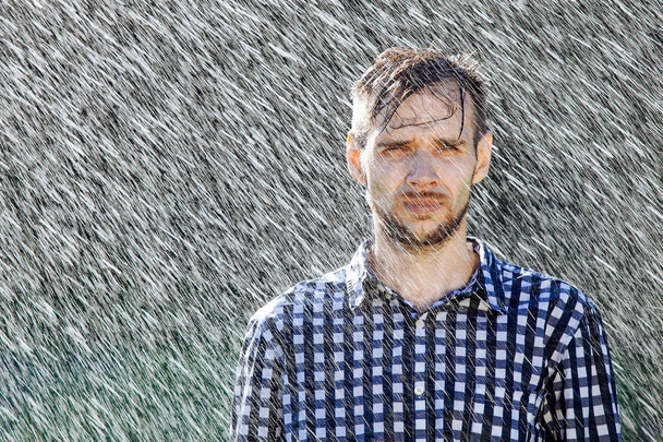 Hattupäinen maanviljelijä nauttii sateesta. Nuori mies kastuu sateen alla kesällä
. - Valokuva, kuva