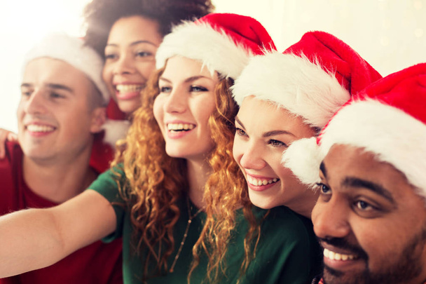 happy friends in santa hats at christmas party - Foto, Imagen