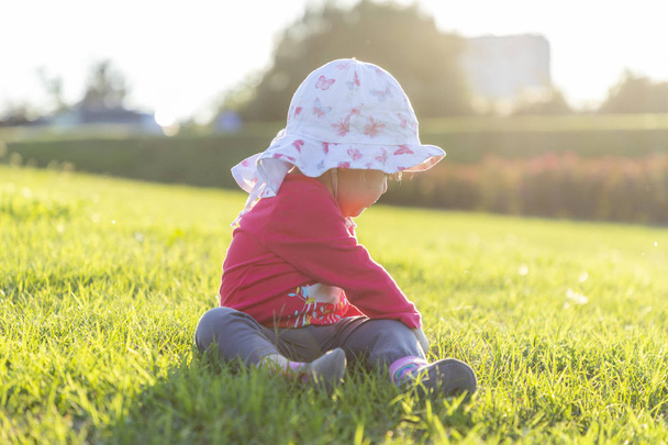 Bambino felice seduto in un'erba in una giornata di sole
 - Foto, immagini