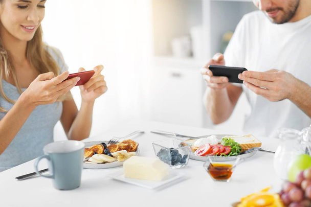 close up of couple with smartphones at breakfast - Fotoğraf, Görsel