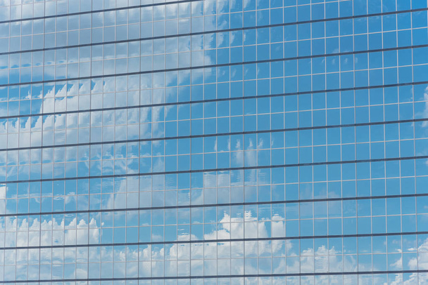 アメリカの近代的なビジネスビルのガラスの壁の雲の反射のクローズ アップの詳細のショット。鉄骨高層商業高層ビル、未来の都市の明るい青の背景 - 写真・画像
