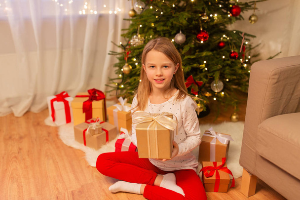 smiling girl with christmas gift at home - Foto, afbeelding