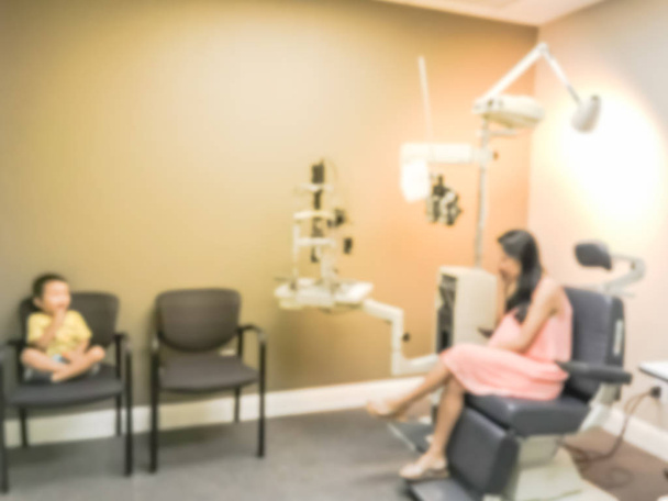 verschwommene abstrakte asiatische Patientin und ihr Kleinkind bei Augen- und Laserspezialisten, die auf ihren Optiker warten, der sie untersucht - Foto, Bild