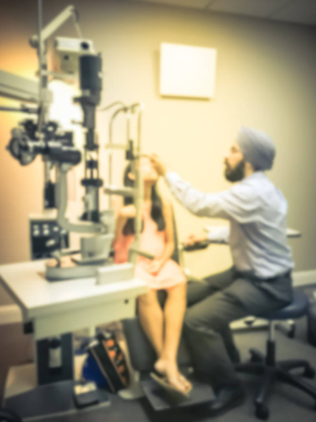 Movimiento borrosa mujer asiática paciente que tiene sus ojos examinados por un optometrista utilizando equipo médico, en la clínica de oftalmología
 - Foto, Imagen