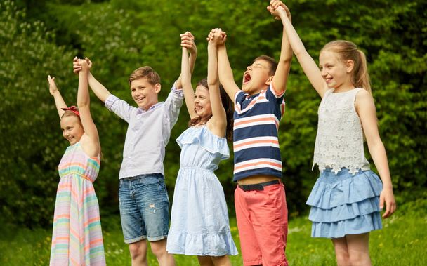 happy kids holding raised hands in summer park - Foto, imagen