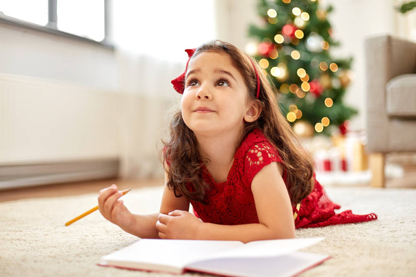 little girl making christmas wish list at home - Фото, изображение