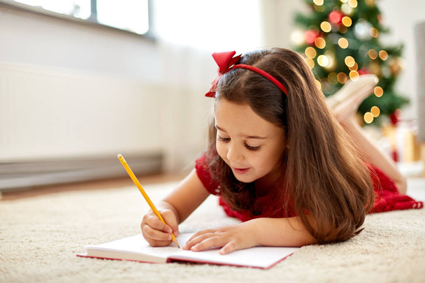 little girl writing christmas wish list at home - Valokuva, kuva