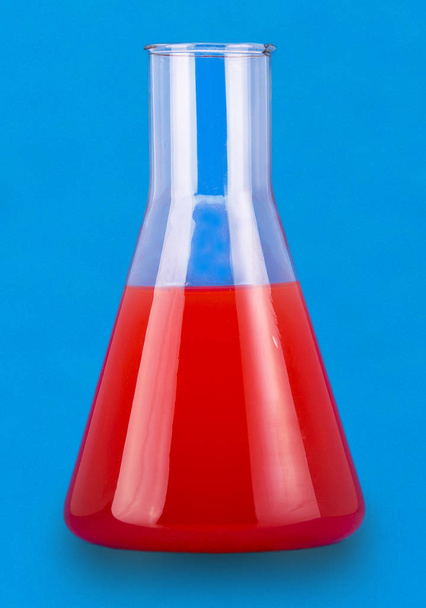 Frasco de ensayo con líquido rojo sobre fondo azul
 - Foto, Imagen