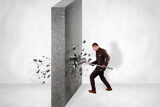 Бизнесмен разбивает стену препятствий, ударяя по ней кувалдой. Концепция преодоления невзгод
 - Фото, изображение