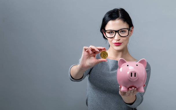 Young woman with bitcoin and a piggy bank - 写真・画像