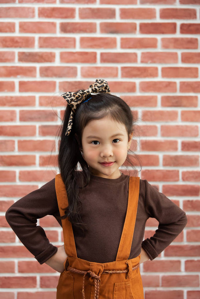 Portrait Little girl standing over brick wall. Looking at camera. Smiling face.  - 写真・画像