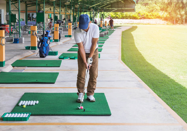 金属ゴルフ クラブ ゴルフ場のヤードの印の範囲を運転の練習中にゴルフボールを駆動するための準備とゴルファー - 写真・画像