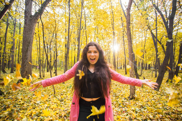 Sonbahar, mutluluk, insanlar kavramı - genç kadın sonbahar parkta eğleniyor. O bir gökyüzünde sarı yapraklar atıyor - Fotoğraf, Görsel