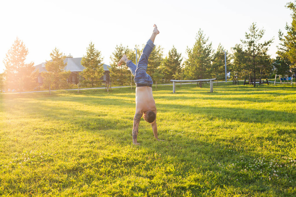 Yoga, fitness y concepto de estilo de vida saludable - el hombre haciendo un handstand en la naturaleza de verano
 - Foto, imagen