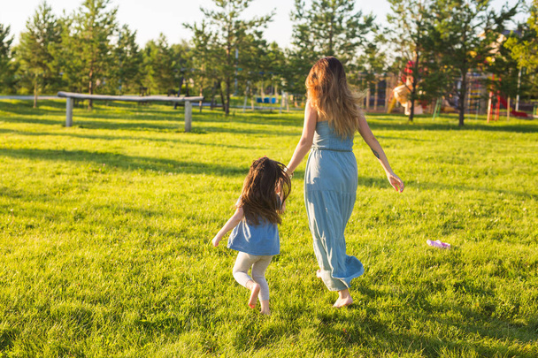 Familien- und Kinderkonzept - Mutter und Tochter spazieren im Park und genießen die schöne Natur. - Foto, Bild