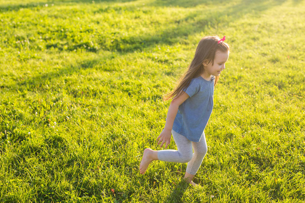 Little happy girl having fun in a summer park. - Foto, Bild