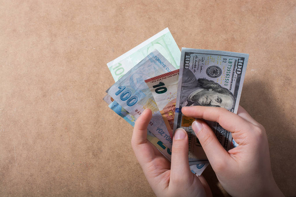 Hand-holding Amerikaanse dollar bankbiljetten geïsoleerd op houten achtergrond - Foto, afbeelding