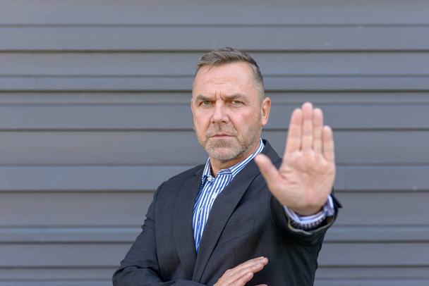 Серйозний зрілий чоловік, що показує стоп жест рукою, фокус на обличчі
 - Фото, зображення