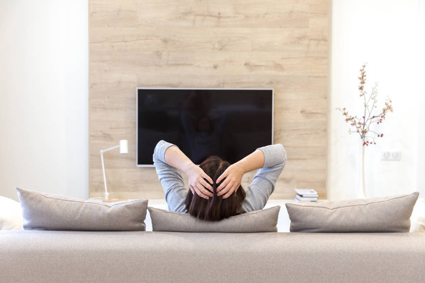 Fiatal nő TV-t néz a szobában - Fotó, kép