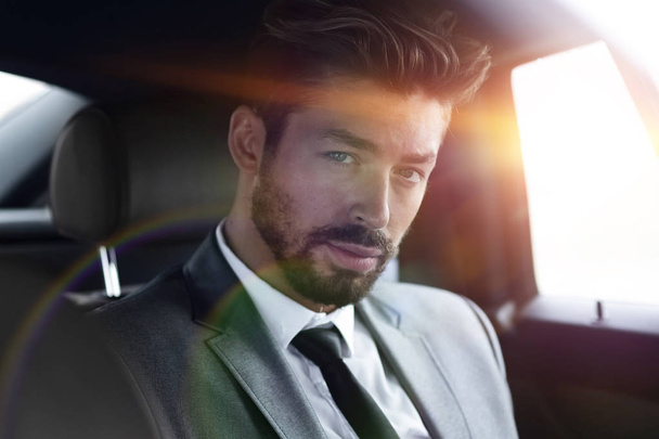 Επιχειρηματία στο κομψό κοστούμι στο πίσω κάθισμα του αυτοκινήτου - Φωτογραφία, εικόνα