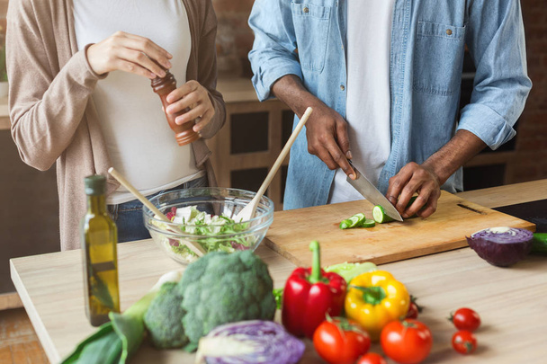 Couple noir préparant une salade de légumes saine en cuisine
 - Photo, image