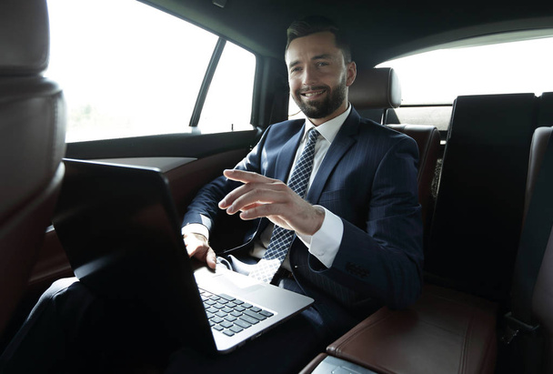 бізнесмен сидить на задньому сидінні в машині і вказує пальцем вперед
 - Фото, зображення