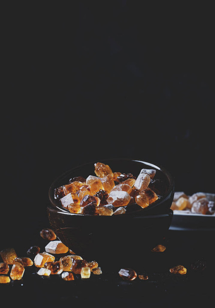 Brown candy cane sugar in bowl on black table, selective focus - Fotoğraf, Görsel