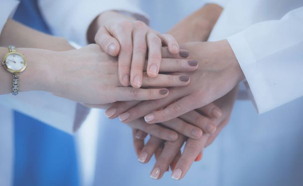 Doctors and nurses in a medical team stacking hands - 写真・画像