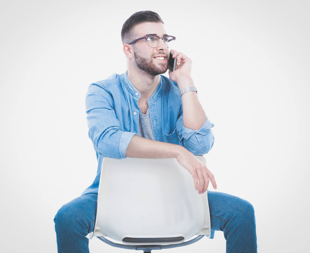 Young man sitting on chair and using mobile phone. Startupper. Young entrepreneur. - Zdjęcie, obraz