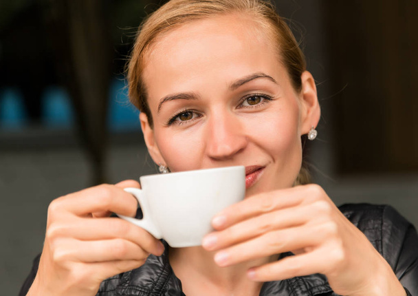 Young beautiful woman with a cup of coffee in a outdoor cafe, girl have a lunch on terrace - Foto, afbeelding