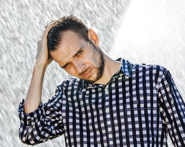 Vahvan, likaisen miehen muotokuva sateessa. Nuori mies kastuu sateen alla kesällä
. - Valokuva, kuva