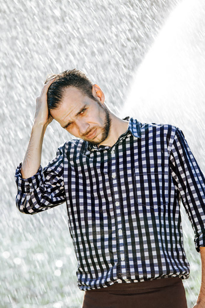 Retrato de un hombre fuerte y empapado bajo la lluvia. Joven mojándose bajo la lluvia en verano
. - Foto, Imagen