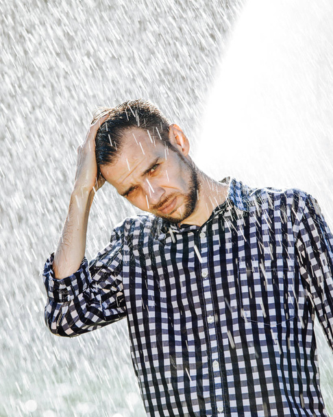 Πορτρέτο ενός ισχυρού, βουτηγμένος ο άνθρωπος μέσα στη βροχή. Νεαρός άνδρας να βραχούν κάτω από τη βροχή το καλοκαίρι. - Φωτογραφία, εικόνα