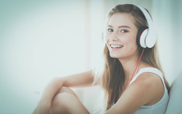 Portrait of beautiful woman in morning listening music sitting on bed at home - Photo, Image