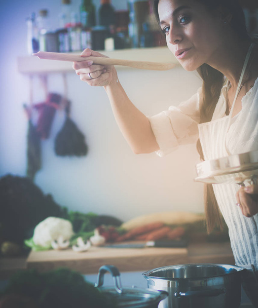 Cooking woman in kitchen with wooden spoon - Fotoğraf, Görsel