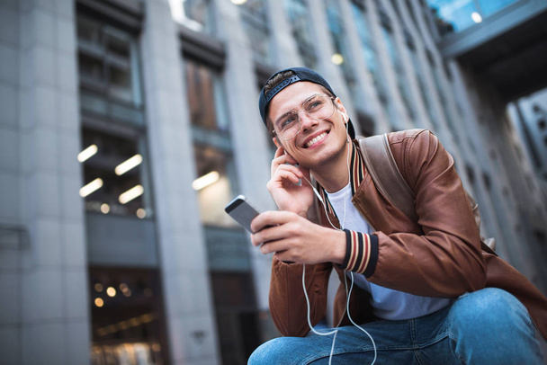 Muž sedící poslechu hudby sluchátka koncept. Veselý mladý muž poslechu hudby. - Fotografie, Obrázek