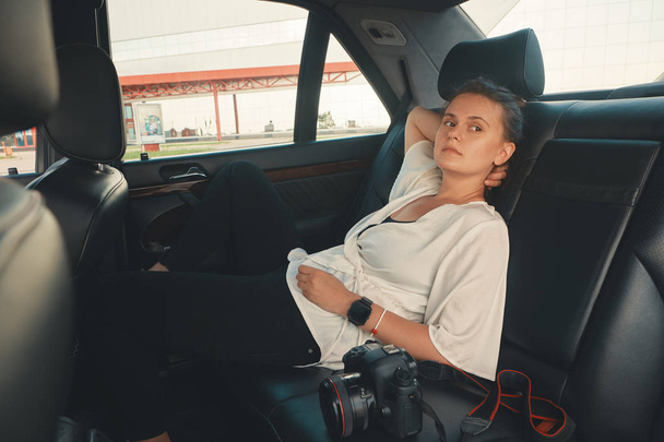 Σύγχρονη γυναίκα που κάθεται στο πίσω κάθισμα του αυτοκινήτου σε οδικό ταξίδι χαλάρωσης - Φωτογραφία, εικόνα