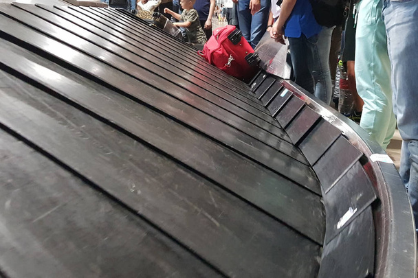 Колесный чемодан на багажном поясе в терминале аэропорта
 - Фото, изображение