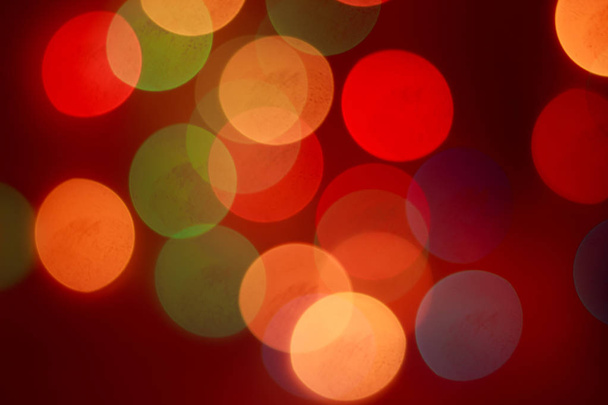 New Year's bokeh. Nieuwjaar. Bokeh van de lichten van een krans. De lichten zijn op. Feestelijke stemming. Abstractie en achtergrond. Rode achtergrond - Foto, afbeelding