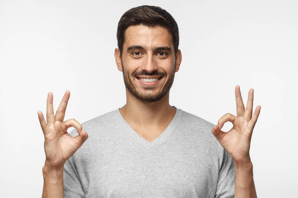 Добре виглядає усміхнений чоловік, що показує знак " Гаразд" двома руками
 - Фото, зображення