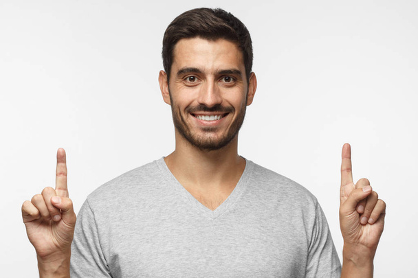 Handsome male pointing up with two fingers, isolated on gray background - Foto, Bild