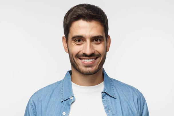 Headshot of young handsome man isolated on gray background, wearing casual blue shirt, smiling happily and friendly at camera - Fotografie, Obrázek