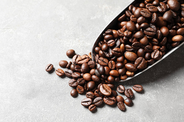 Scoop with roasted coffee beans on grey background, closeup - Photo, Image