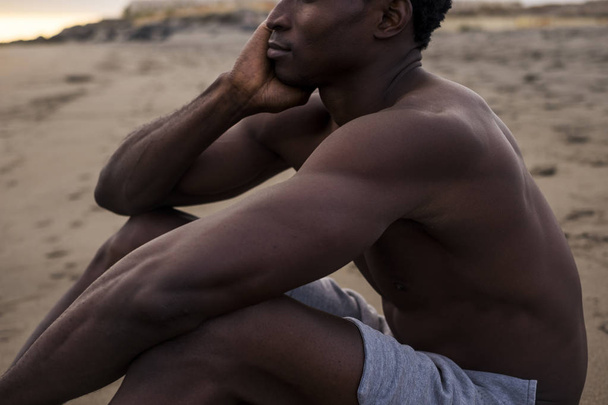 retrato de un atleta africano descansando en la playa
 - Foto, imagen
