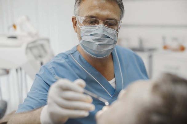Close up of dentist in blue uniform checking up client teeth health condition. - Φωτογραφία, εικόνα