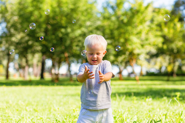 Little boy catching beautiful soap bubbles outside - Photo, image