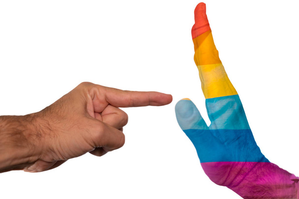 Finger pointing to a peaceful hand with pride flag isolated on a white background. Intolerance against gay community and discrimination concept. - Photo, Image