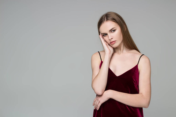 Young model long-haired blond girl in dard red dress poses showing emotions - Фото, зображення