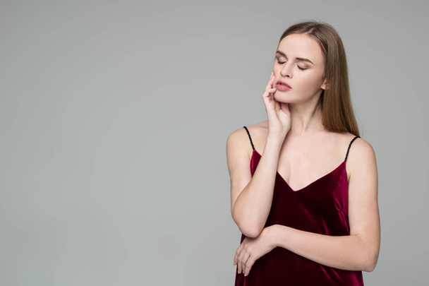 Young model long-haired blond girl in dard red dress poses showing emotions - Fotoğraf, Görsel